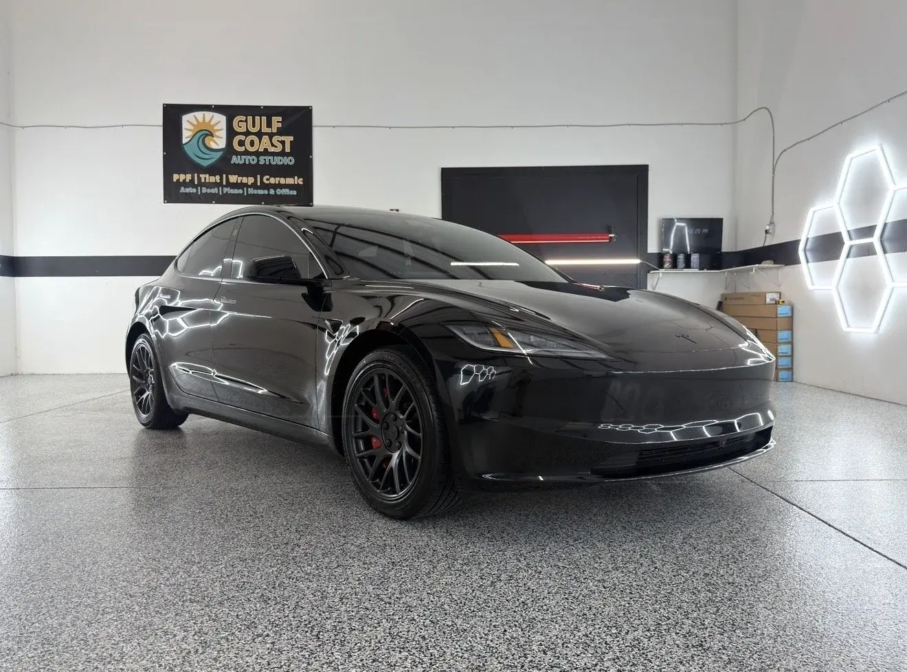 Black Tesla Model Y in the Gulf Coast Auto Studio bay in Sarasota