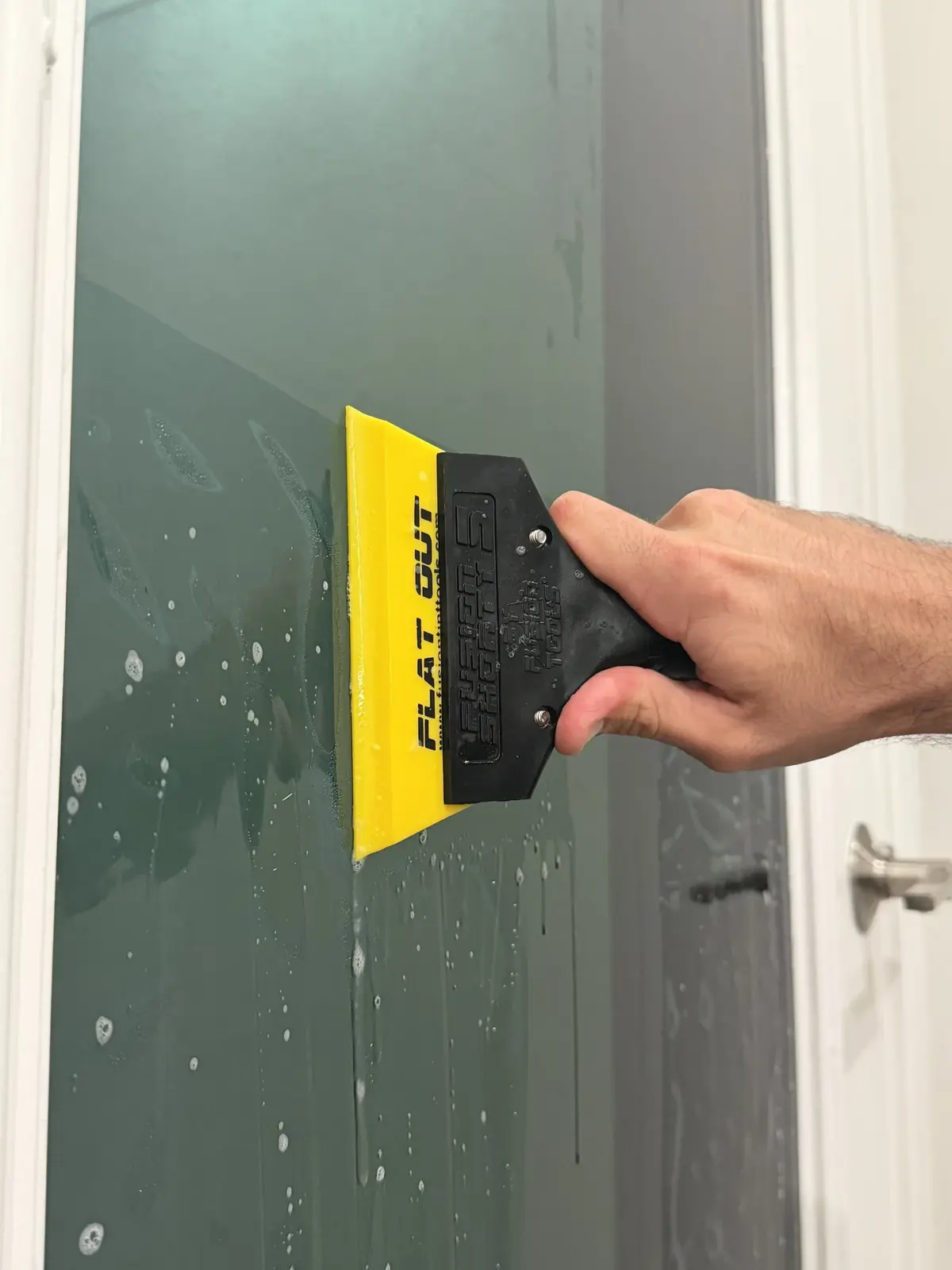 Installer squeegeeing window film onto a car window