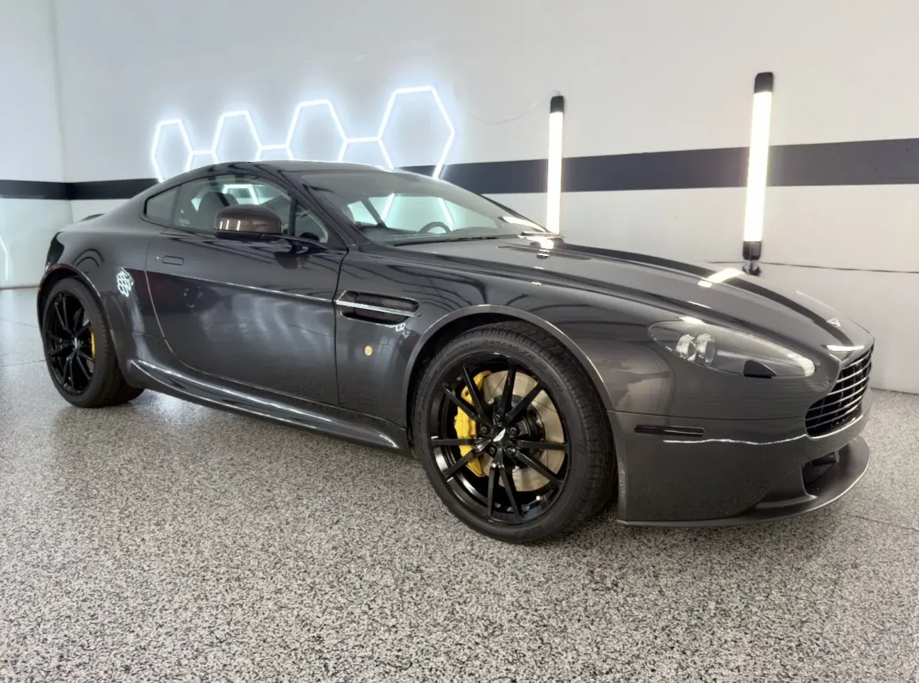 Gray Aston Martin Vantage with yellow brake calipers in the Gulf Coast Auto Studio bay