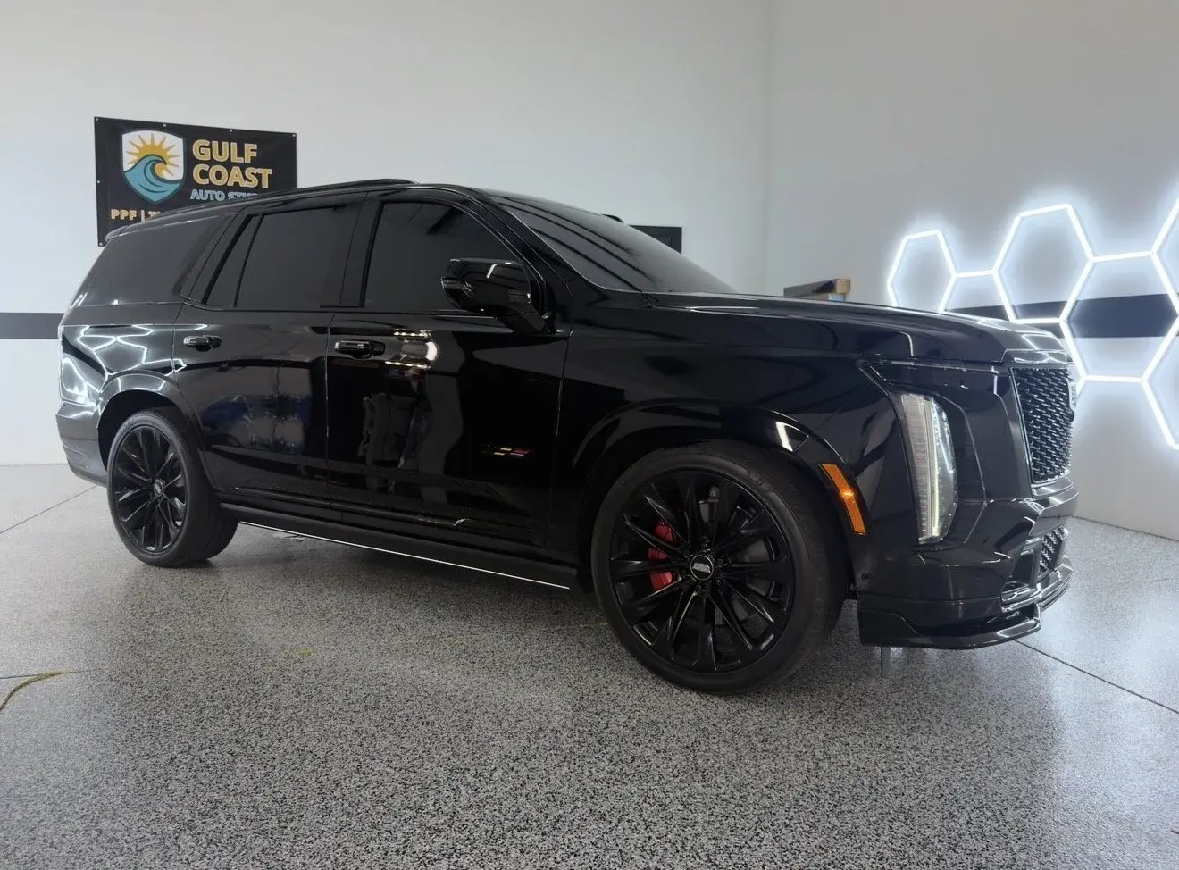 Black Cadillac Escalade with glossy paint in the Gulf Coast Auto Studio bay