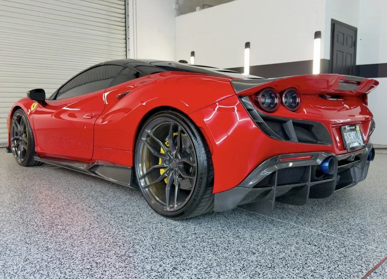 Rear of a red Ferrari with carbon aero parts in the studio