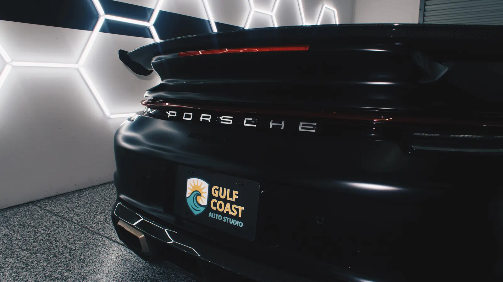 Black Porsche 911 rear with Gulf Coast Auto Studio plate in the studio