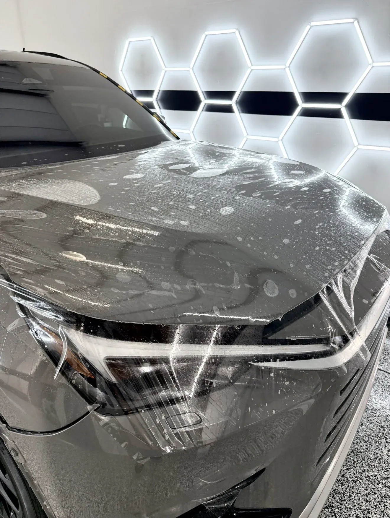 Paint protection film being fitted to the front of a gray car