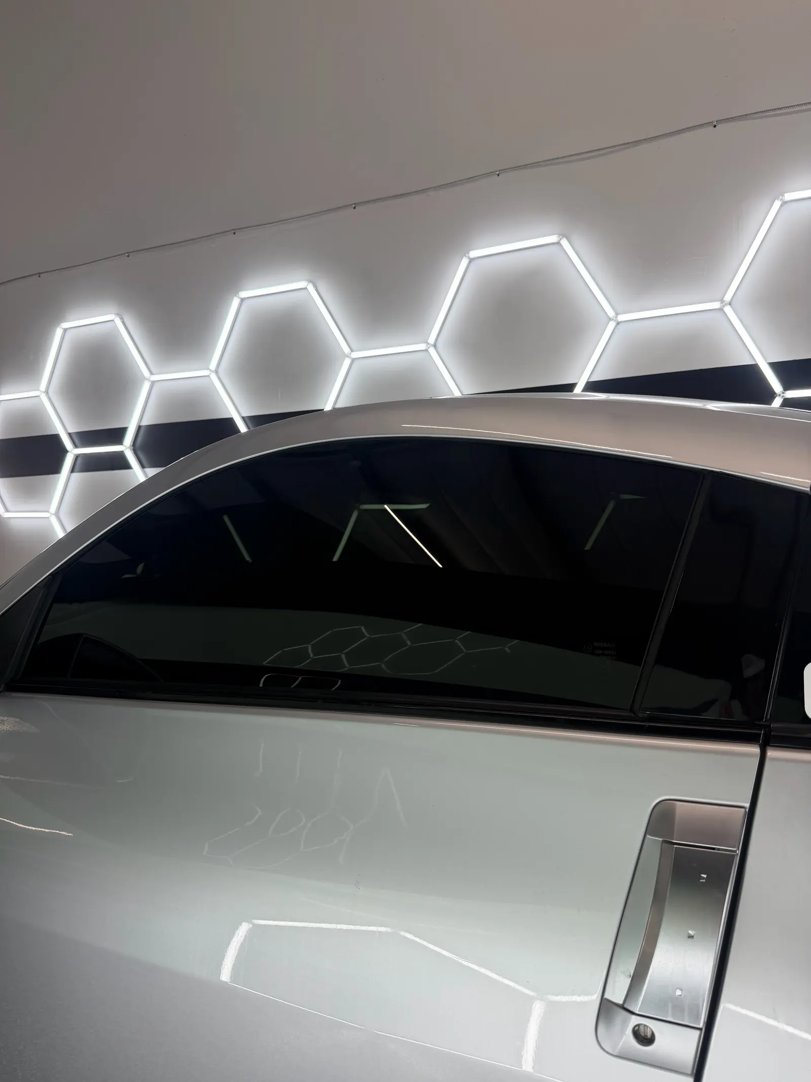 Silver car with dark window tint reflecting the studio hex lights
